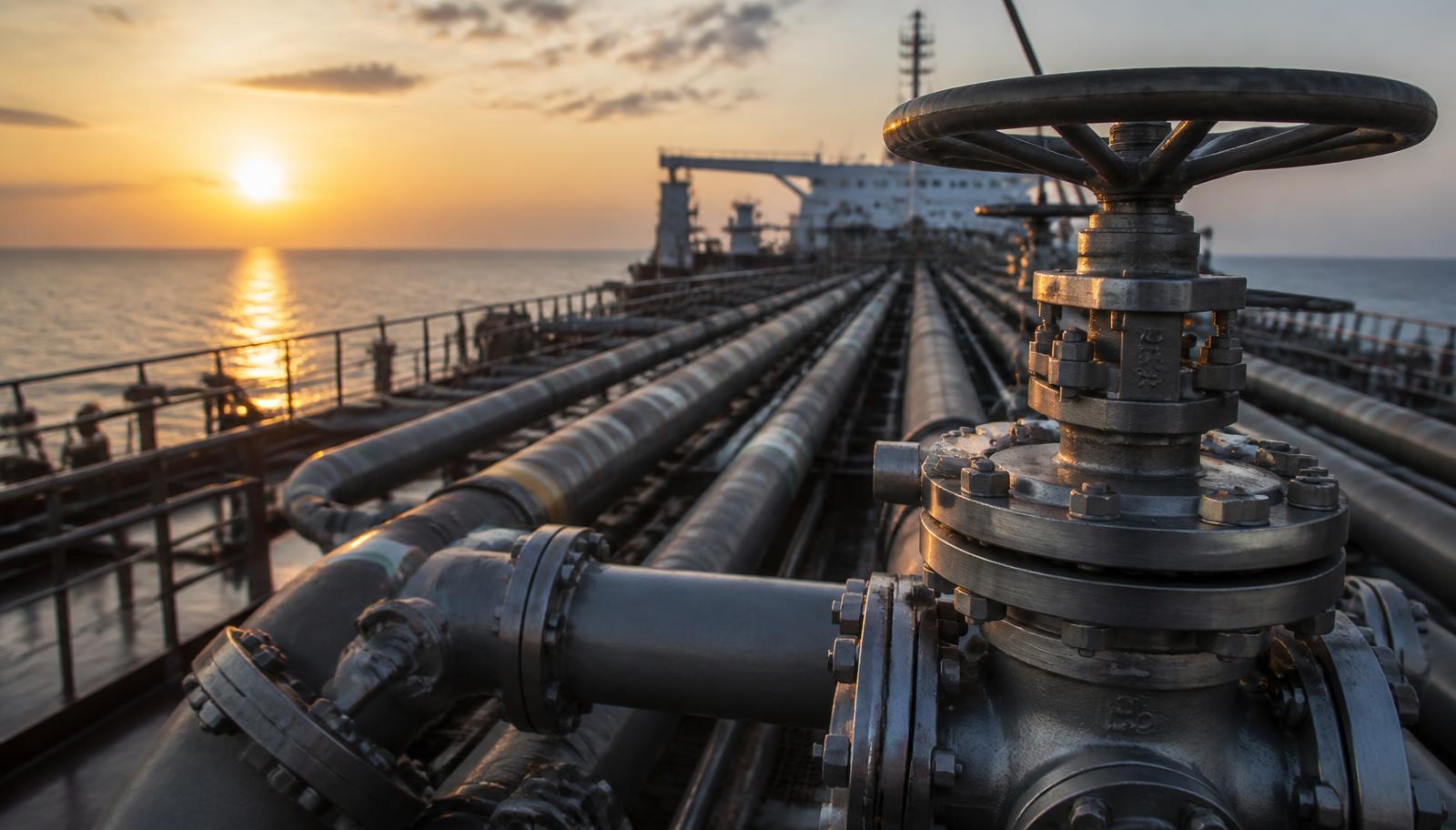 Tuyauteries et vannes de cargaison sur le pont d'un pétrolier au lever du soleil